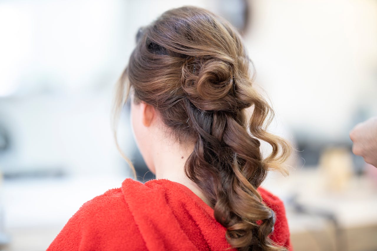 about-me-01 Close-up of an elegant bridal hairstyle featuring curls and a braid, captured from the back.